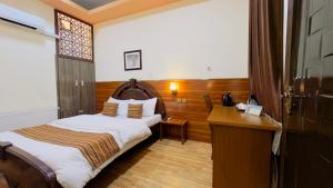 喀布尔Khyber Hotel的配有一张床和一张书桌的酒店客房