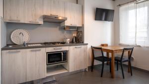 佩斯基耶拉德加达Fiori sull'Acqua Apartments的厨房配有木制橱柜和桌椅