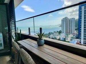 归仁Wins House - FLC Sea Tower Quy Nhơn的阳台上的木桌和盆栽植物