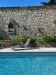 拉弗洛特VILLA DEL RE 3 face à la piscine的石墙和游泳池旁的椅子