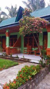 武吉拉旺Wisma Batu Mandi and offers jungle tours的前面有长凳和鲜花的绿色房子