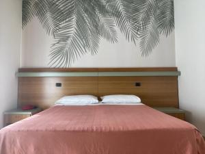 罗索利纳马雷Hotel Pine Beach的一间卧室配有一张带粉红色床罩的床