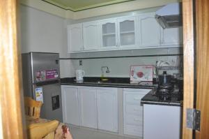 奥鲁罗COMODORO DEPARTAMENTOS的厨房配有白色橱柜和不锈钢冰箱