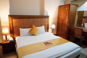 伊斯兰堡Midtwon Hotel Islamabad的一间卧室配有一张大床和木制床头板