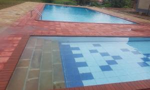 马查科斯Lysak Haven Park hotel的一座铺有砖地板和蓝色瓷砖的游泳池
