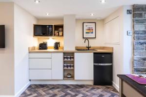 MiddletonThe Holt - Ilkley, central location, stylish apartment的厨房配有白色橱柜和黑色冰箱。