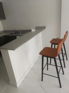 朱菲尔Infinity Juffair Suites的厨房配有带椅子和桌子的柜台