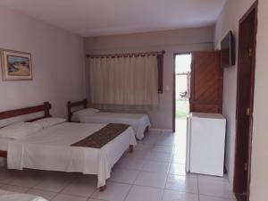 新维索萨Pousada Cheiro de Mar的一间卧室配有两张床、一台电视和一台冰箱