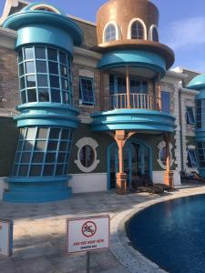 后川Wonderland Villa Hồ Tràm Beach的游泳池前有标志的建筑物