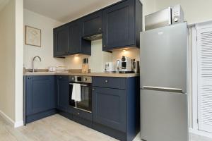 考斯West Cowes Penthouse的厨房配有蓝色橱柜和冰箱。