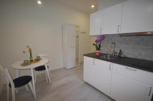 克拉科夫Central Cracow Apartments的厨房配有白色橱柜、桌子和水槽。
