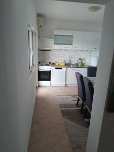 蒂瓦特Apartment Potpara的厨房配有白色橱柜和桌椅