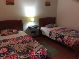 圣地亚哥-杜卡森Country House Porto Covo, Monte da Casa Velha的客房设有两张床和一张带台灯的桌子。