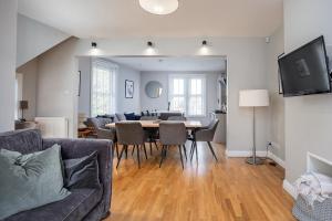 谢菲尔德Stylish and Spacious 3 Bed Apartment with Parking by Ark SA的用餐室以及带桌椅的起居室。