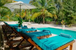 江比阿Villa Passiflora Zanzibar的游泳池旁的一组带遮阳伞的躺椅