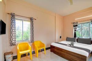 ThākurdwariArhan Villa Inn Kolkata - Excellent Customer Choice - Best Seller的一间卧室配有一张床和两张黄色椅子