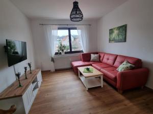 鲁多尔施塔特Ferienwohnung Cumbach的客厅配有红色的沙发和桌子