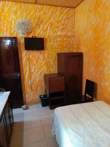 帕潘特拉德奧拉特Posada Familiar Papantla的一间卧室配有一张床、一张书桌和一台电视。
