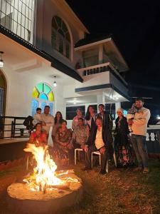 乌提Hestia Chalet 3BHK Villa的一群人坐在房子前的火堆旁