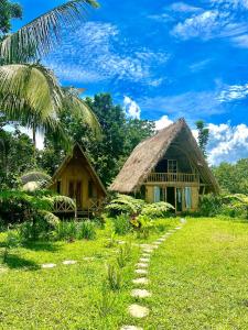 特特巴图Girang Rinjani Bungalows的茅草屋顶和小路的房子