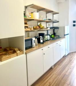 罗马Lexie Suites的厨房铺有木地板,配有白色橱柜。
