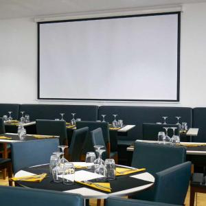 巴拉吕克莱班LE CENTRAL HOTEL BAR RESTAURANT的一间带桌椅和大屏幕的用餐室