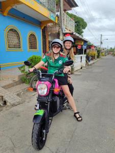 莫约加尔帕Guest House Nena的两个女孩坐在街上的摩托车上
