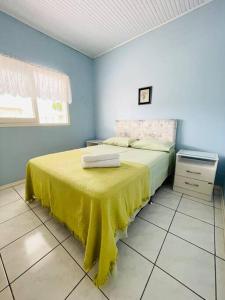 阿罗约多萨尔Casa de Praia Aconchegante e Próxima da Praia的一间卧室配有一张黄色毯子床