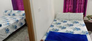 瓦加蒙Silver home stay vagamon的一间卧室配有两张带蓝白色床单的床