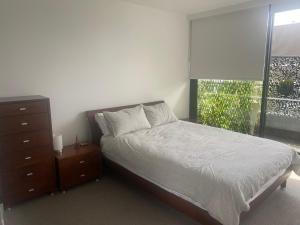 墨尔本Spacious 2 bed apartment, great location的一间卧室配有一张床、一个梳妆台和一扇窗户。