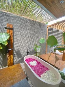 KemiriAkaya Villas Solo的庭院里设有装满粉红色花卉的浴缸。