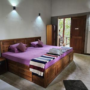库鲁内格勒THE HIDEOUT KURUNEGALA的一间卧室配有一张大木床和紫色床单
