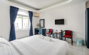 胡志明市La Casona Boutique Hotel的一间卧室配有白色的床和两张红色椅子