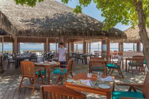 拉斯杜Veligandu Maldives Resort Island的站在餐厅前的男人,有桌椅