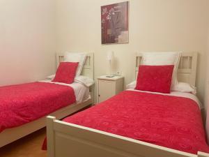 扎马亚Apartamento Costa con Parking Privado Incluido的卧室内的两张红色床罩