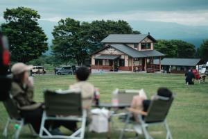 竹田Boiboi Camp site Surrounded by Japanese Nature的一群人坐在房子前面的桌子旁