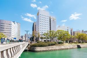 广岛Hiroshima Intelligent Hotel Annex的一座建有建筑物的城市里河流上的桥梁