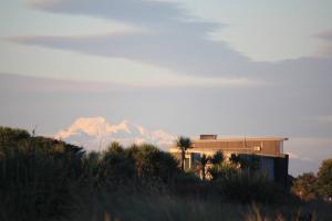 霍基蒂卡Hokitika Beach Break的远处的山,有一座建筑和棕榈树