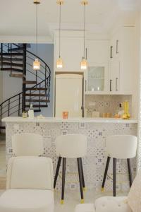 马赫迪耶Maison SOUAD的厨房配有3把白色椅子和台面