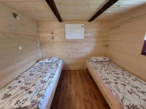 Gorenja VasGlamping Laze的木制客房内的一间卧室配有两张床