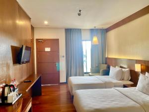 三宝垄Oak Tree Emerald Semarang的酒店客房设有两张床和电视。
