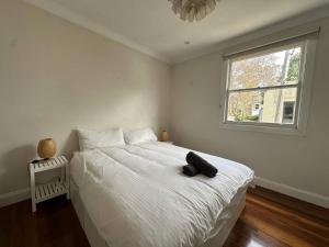 悉尼3 Bedroom House Family Friendly Surry Hills 2 E-Bikes Included的卧室配有一张白色床,上面有黑色帽子