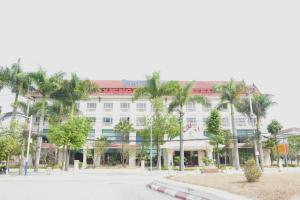 Ban NafèngCoecco Xieng Khouang Hotel的一座白色的大建筑,前面有棕榈树