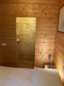 MatslootLuxe en ruim chalet met airco bij Leekstermeer的卧室设有木墙和白色的床。