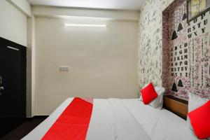 斋浦尔Flagship Hotel Big Vine的一间卧室配有一张带红色枕头的床和一面墙