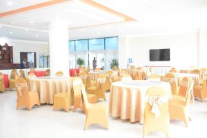 Ban NafèngCoecco Xieng Khouang Hotel的宴会厅配有桌椅和平面电视。