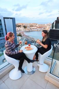 圣朱利安斯马耳他智选假日酒店的两个女人坐在阳台上的桌子上吃食物
