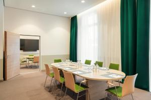 吕贝克IntercityHotel Lübeck的一间会议室,配有桌子和绿色椅子