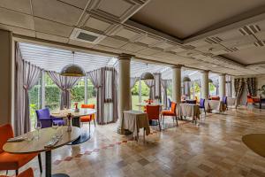 沙布利Logis Hostellerie des Clos et restaurant Bistrot des grands crus的餐厅设有桌椅和窗户。