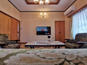 OchiCarpe Diem Kamaida的客厅配有电视和桌椅